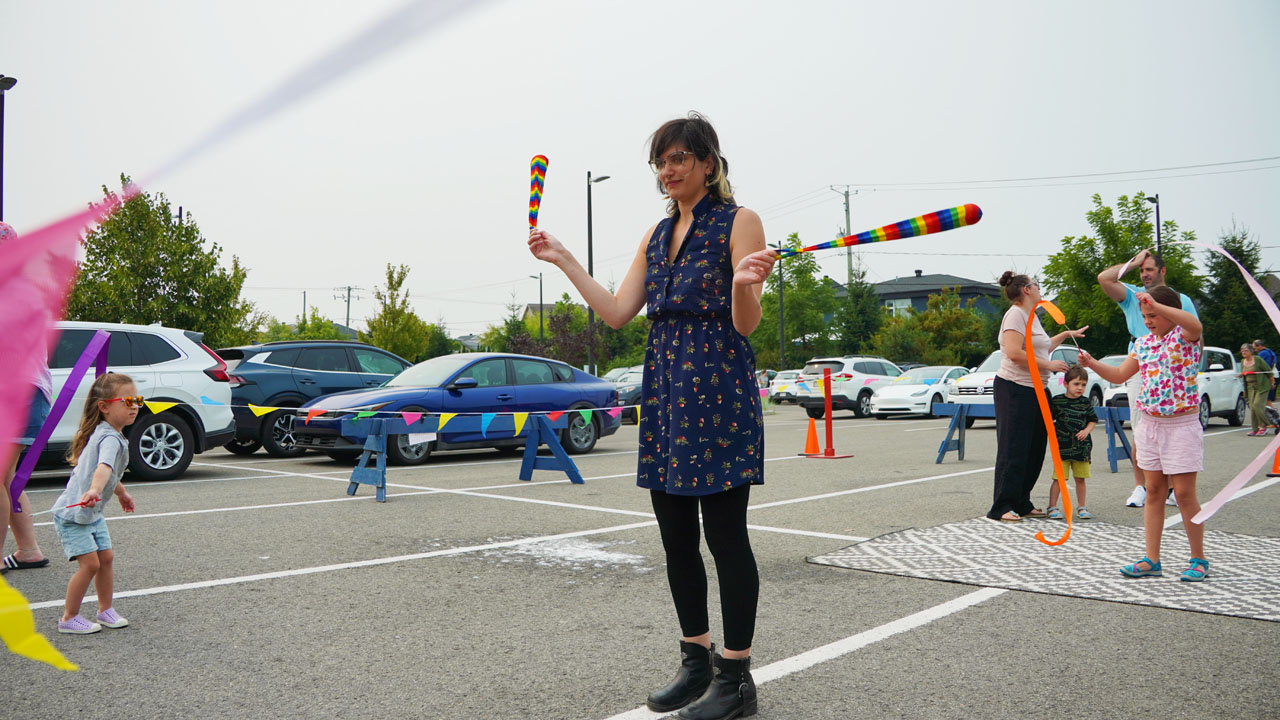 Adulte s'initiant à la manipulation d'un bâton fleur dans un kiosque d'animation de cirque pour événement corporatif et familial.